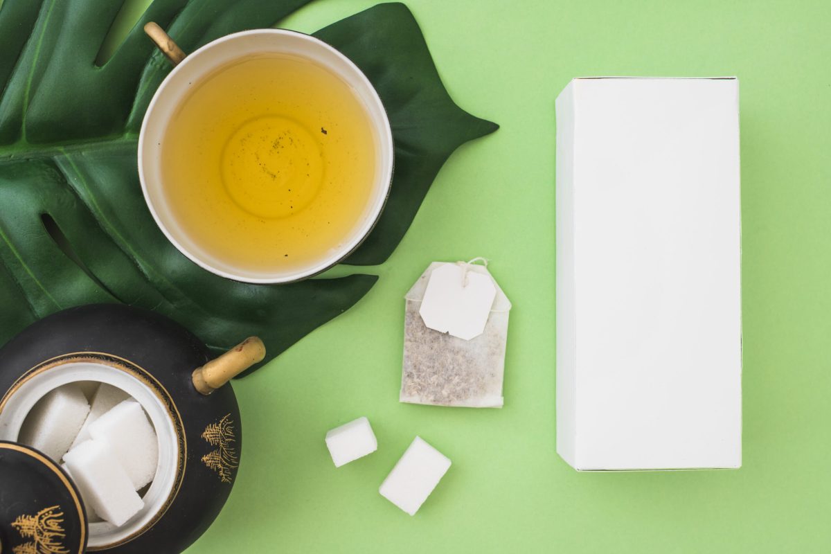 overhead-view-herbal-tea-cup-with-sugar-cubes-tea-bag-box-green-background eye skin